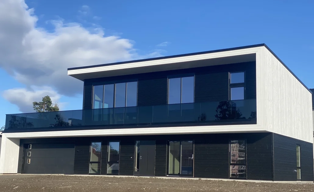 Stolpefritt glassrekkverk i eloksert aluminium og 17,52 mm sotet herdet og laminert glass. Svart bunnskinne og svart håndløper. Moderne glassrekkverk.