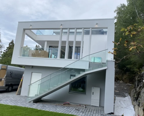 Stolpefritt glassrekkverk i eloksert aluminium og 17,52 mm klart herdet og laminert glass. Montert på utendørs trapp. Trapperekkverk.